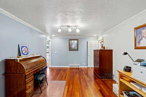 Main floor - Office/formal dining with dark wood finished floors, a textured ceiling, crown molding, and recessed lighting