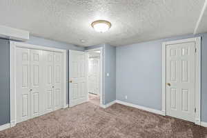 Unfurnished bedroom with a textured ceiling, carpet flooring, and a closet