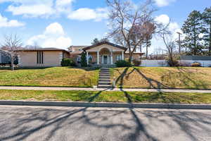 View of front of home featuring covered porch, a front yard, and brick siding