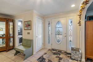 Entrance foyer with crown molding, light tile patterned floors, and a textured ceiling