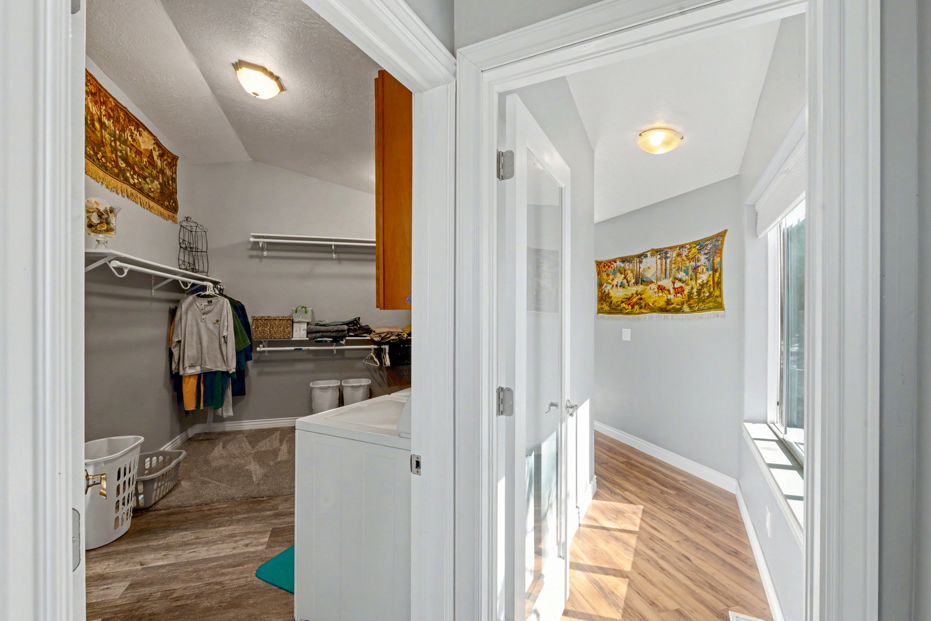 Walk in closet with light wood finished floors, washer / clothes dryer, and lofted ceiling