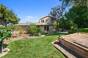 Back of house featuring a yard, a patio area, and brick siding