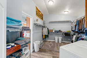 HUGE Walk in closet featuring washer / dryer, vaulted ceiling, and light wood-style flooring