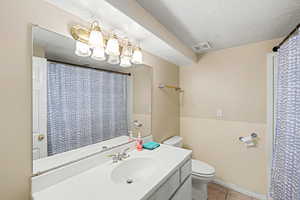 Full bathroom with vanity, a textured ceiling, a shower with shower curtain, and light tile patterned floors
