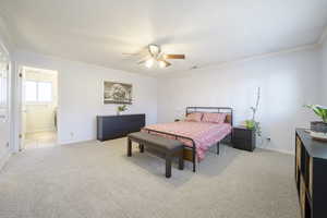 Bedroom featuring light colored carpet, crown molding, ceiling fan, and connected bathroom