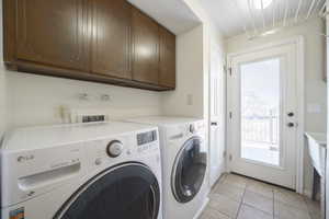 Laundry area featuring cabinet space, washing machine and clothes dryer, and light tile patterned floors