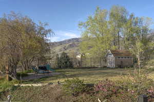 Fenced backyard with a mountain view, a shed, and a patio area
