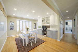 Dining area featuring built in study area, ornamental molding, a textured ceiling, light wood-style flooring, and recessed lighting