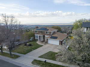 View of front of house featuring a chimney, roof mounted solar panels, a front yard, concrete driveway, and a garage