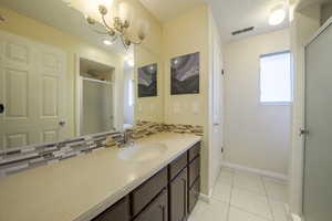 Full bathroom with backsplash, vanity, a shower stall, light tile patterned floors, and a textured ceiling