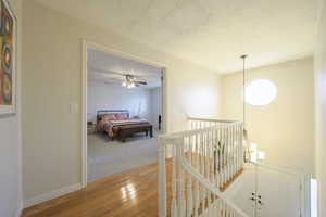 Hallway featuring hardwood / wood-style floors, a textured ceiling, an upstairs landing, and a chandelier