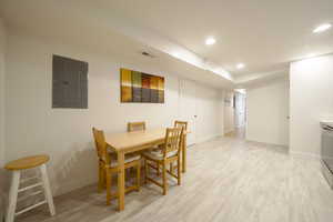Dining space featuring electric panel, light wood finished floors, and recessed lighting