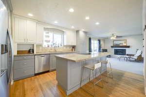Kitchen featuring stainless steel appliances, light wood finished floors, a kitchen breakfast bar, light stone countertops, and open floor plan