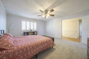 Bedroom with a textured ceiling, crown molding, carpet, and ceiling fan