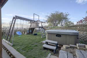 View of yard with a playground and a hot tub