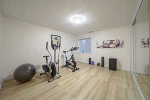 Exercise room with a textured ceiling and light wood-style floors