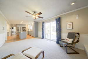 Living room featuring ornamental molding, recessed lighting, light carpet, and ceiling fan