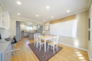 Dining area with ornamental molding, an office area, light wood-style flooring, recessed lighting, and a textured ceiling