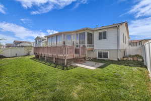 Back of house with a sunroom, a fenced backyard, and a deck