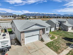 Single story home featuring a residential view, a garage, driveway, and a mountain view