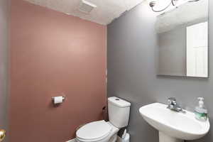Bathroom featuring toilet and a textured ceiling