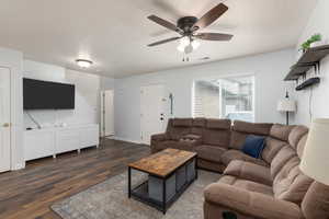 Living room with dark wood-style flooring, a textured ceiling, and ceiling fan