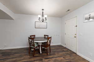 Dining room featuring suspended lighting and dark wood-style flooring