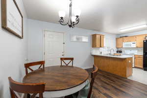 Dining space with dark wood finished floors and a chandelier