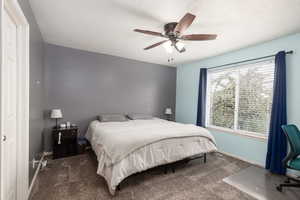 Carpeted bedroom with ceiling fan and a textured ceiling