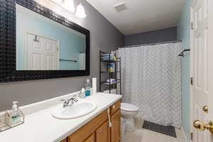 Bathroom with vanity, curtained shower, and a textured ceiling