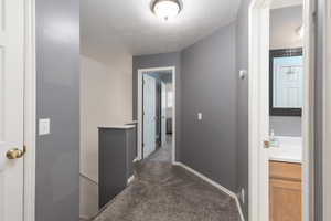 Corridor with dark colored carpet and a textured ceiling