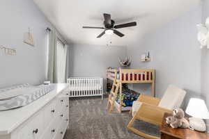 Bedroom with dark carpet, ceiling fan, and a textured ceiling