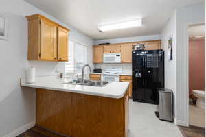Kitchen featuring white appliances, light countertops, and a peninsula