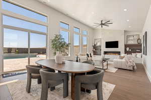 Dining space featuring recessed lighting, wood finished floors, a tile fireplace, a high ceiling, and a ceiling fan