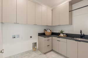 Laundry area with hookup for a washing machine, cabinet space, electric dryer hookup, and light marble finish flooring