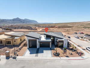 View of front facade with driveway, an attached garage, view of desert, and a mountain view