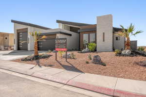 Contemporary house featuring an attached garage, concrete driveway, a chimney, and stucco siding