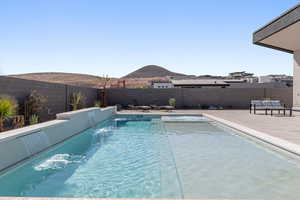 View of swimming pool with a mountain view, a fenced backyard, and patio surround