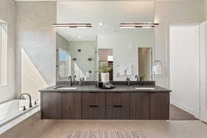 Full bath featuring double vanity, a shower stall, and a bath