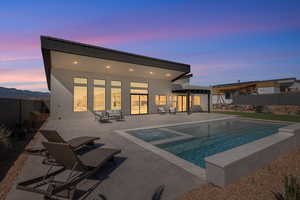 Rear view of house featuring a patio, a fenced backyard, stucco siding, and a pool with connected hot tub