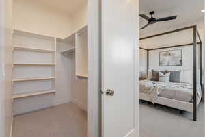 Walk in closet featuring light colored carpet and a ceiling fan