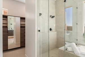 Bathroom with a shower stall, a garden tub, vanity, and a walk in closet