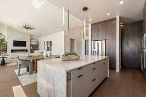 Kitchen featuring modern cabinets, a center island, light stone counters, dark wood finished floors, and open floor plan
