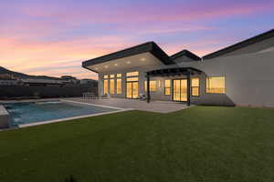 Rear view of property featuring a patio area, stucco siding, a pergola, a fenced backyard, and a pool with connected hot tub