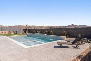 View of swimming pool featuring a fenced backyard, an in-ground hot tub, and patio surround