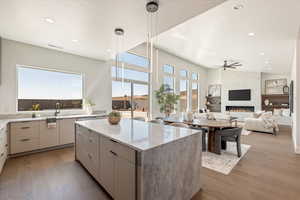 Kitchen featuring light stone countertops, a kitchen island, dark wood-style floors, hanging light fixtures, and a textured ceiling