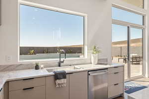 Kitchen with dishwasher, light stone countertops, and modern cabinets