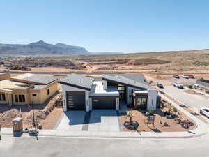 View of front facade featuring a desert view, a garage, concrete driveway, a mountain view, and a view of countryside