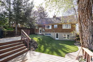 Back of property with brick siding, a chimney, a wooden deck, and a fenced backyard