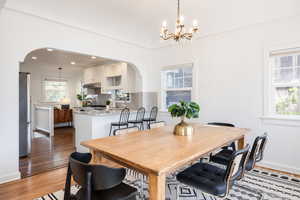 Dining area featuring arched walkways, light wood finished floors, and a chandelier